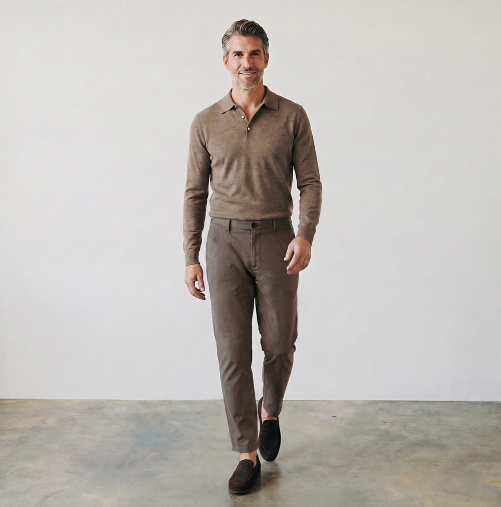 Man wearing a brown sweater and pants walking in a minimalistic setting